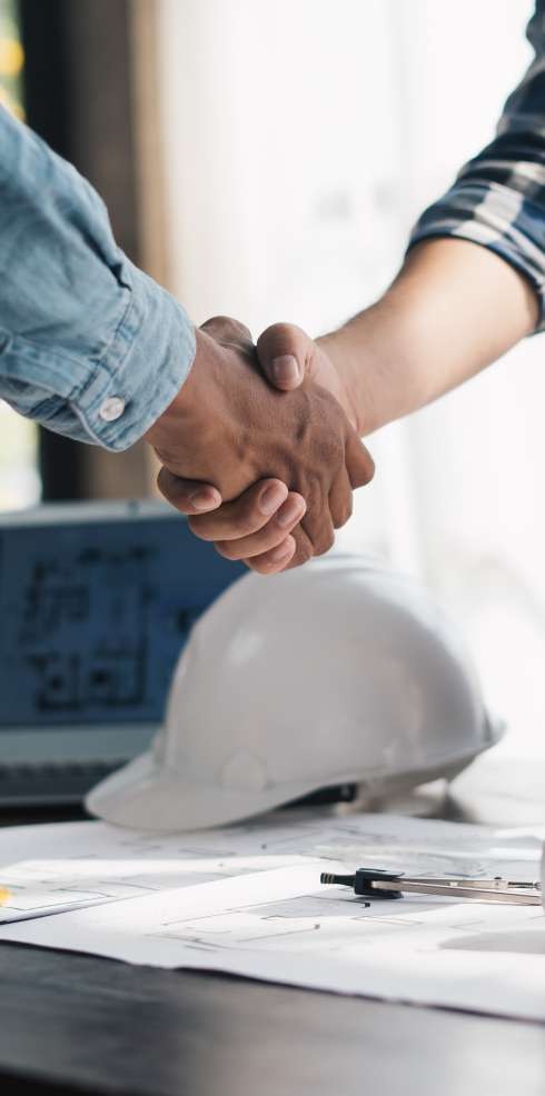 Partnership handshake over construction plans